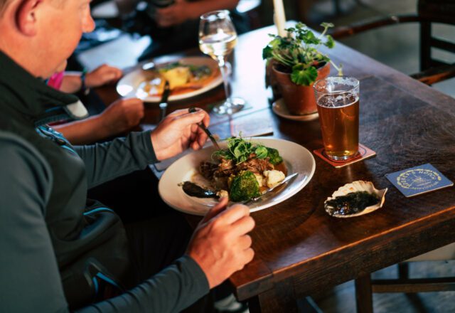 Man eating cooked pub lunch at a table with pint of ale