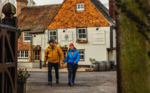 A couple in winter coats walking holding hands in front of the Samuel Palmer pub