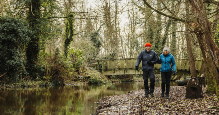 A couple walking alongside the River Darent at Lullingstone on a chilly, autumnal day