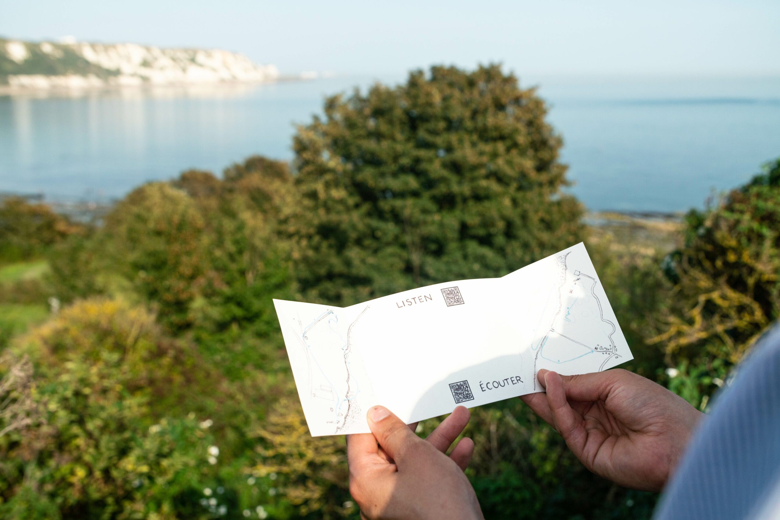 Hands holding a piece of card in front of ocean scenery