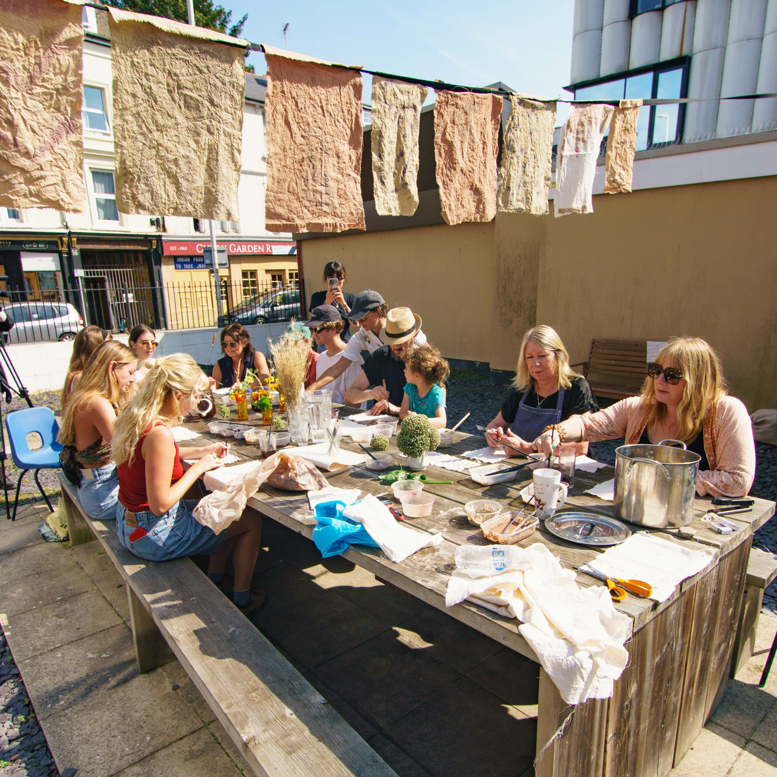 Group of people in an art class working on a table outside