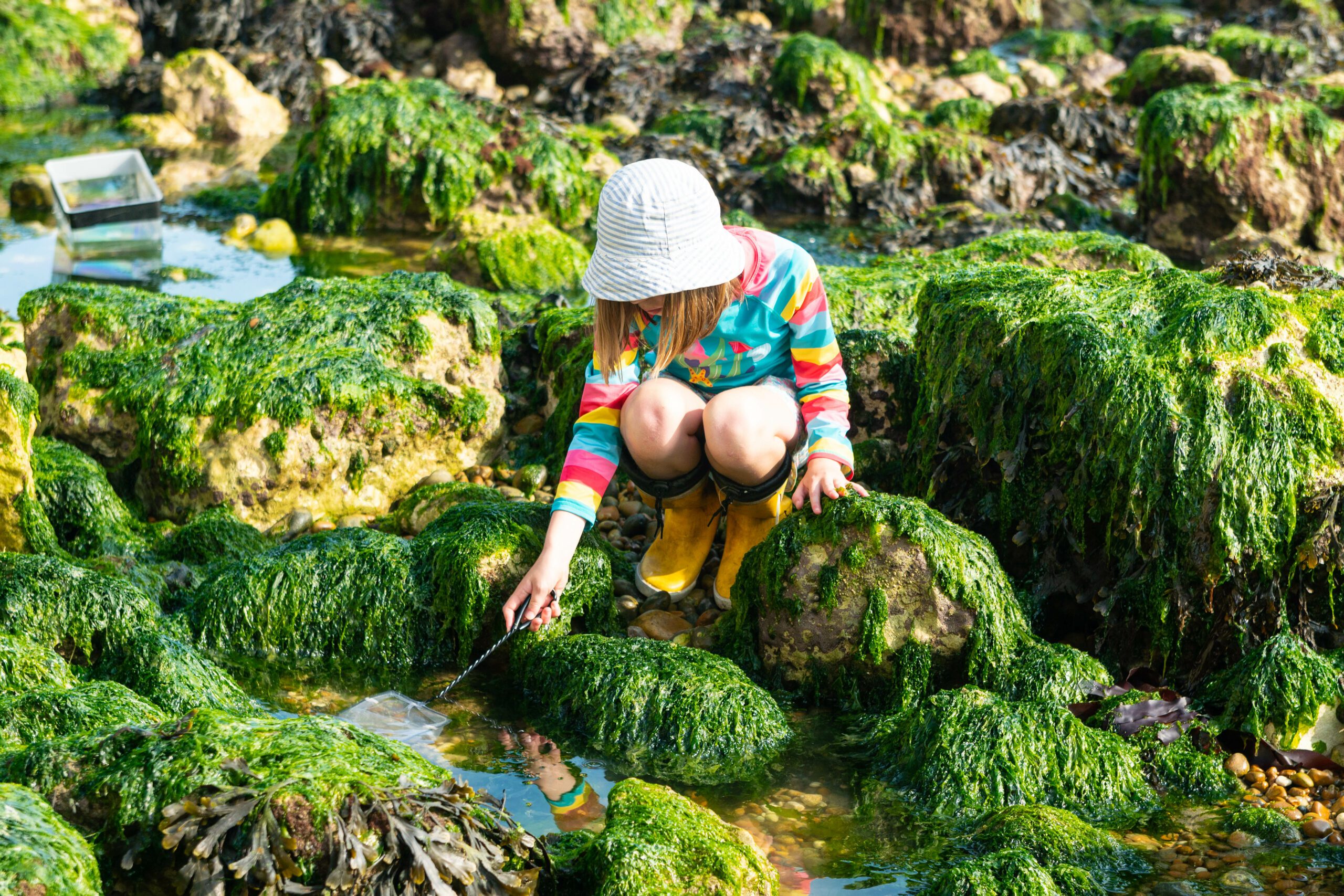 Girl in striped top sitting on mossy rocks