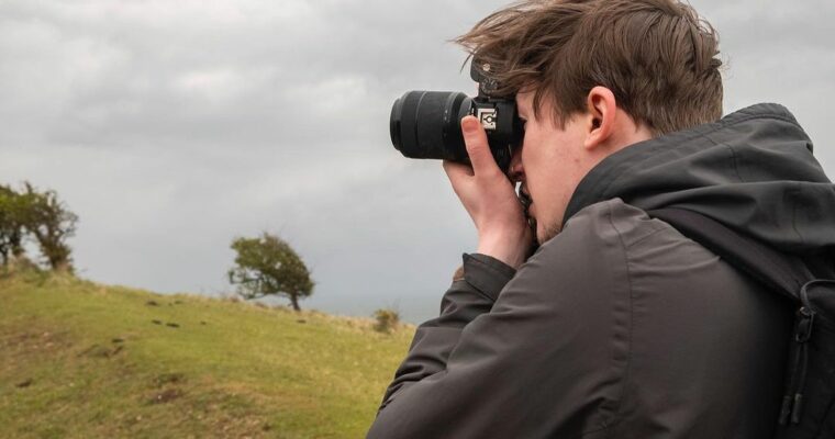 Young man looking through the lens of a camera in the countryside