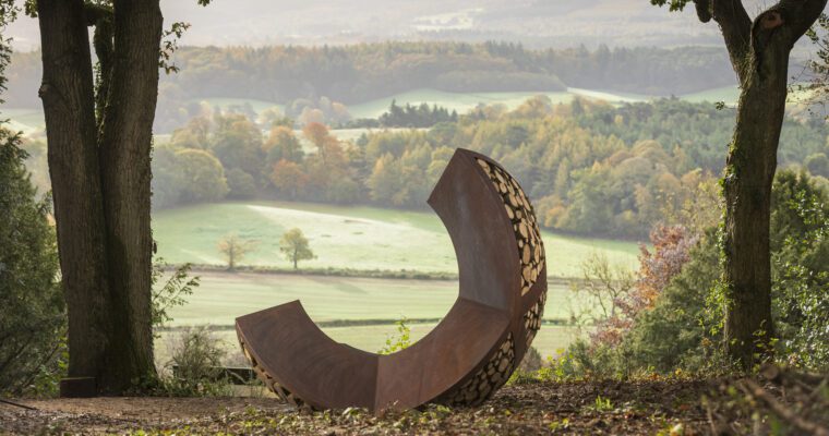 View over Surrey Hills, grass fields and woodland. With Optohedron sculpture in foreground.