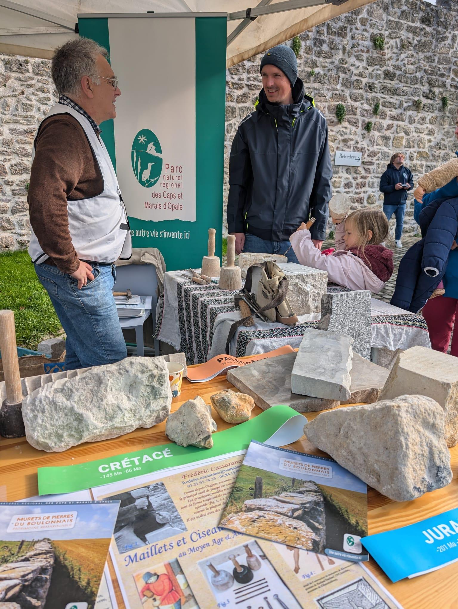 A young girl tries her hand at being a stonemason, carefully chiselling a piece of stone.