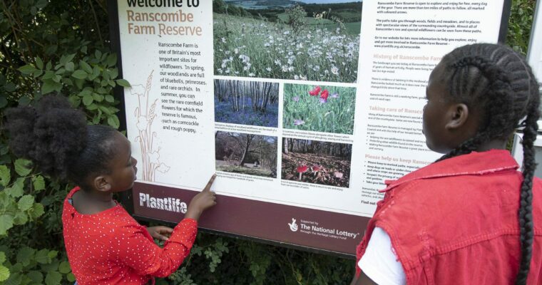 Two children reading an information board for Ranscombe Farm