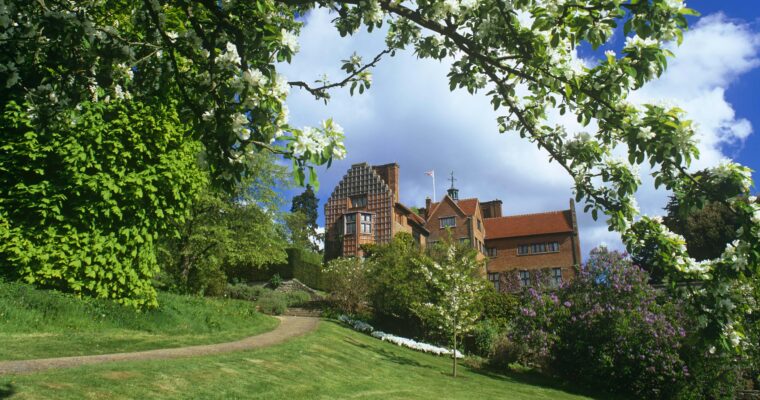 View of Chartwell from the grounds. On a sunny day, with blossom on tree in foreground.