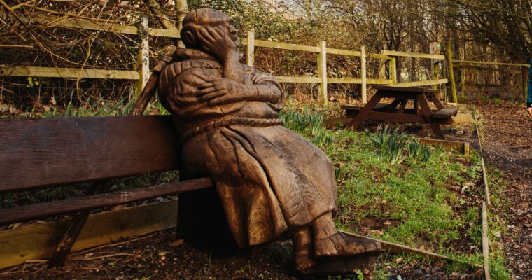 statue of a person sitting on a bench, putting down routes