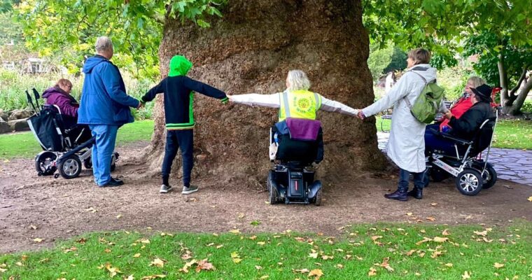 group of people holding hands next to a tree
