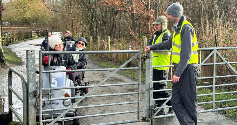 A group of people in mobility scooters navigate a gate as part of a lived experience event.