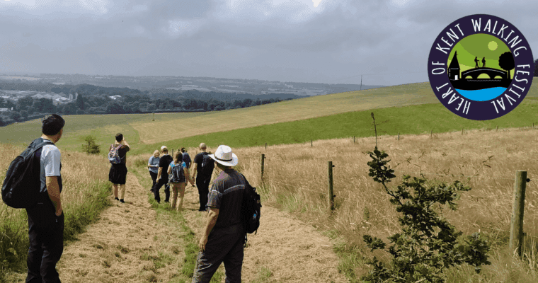 People looking at a countryside view with the Heart of Kent Walking Festival logo