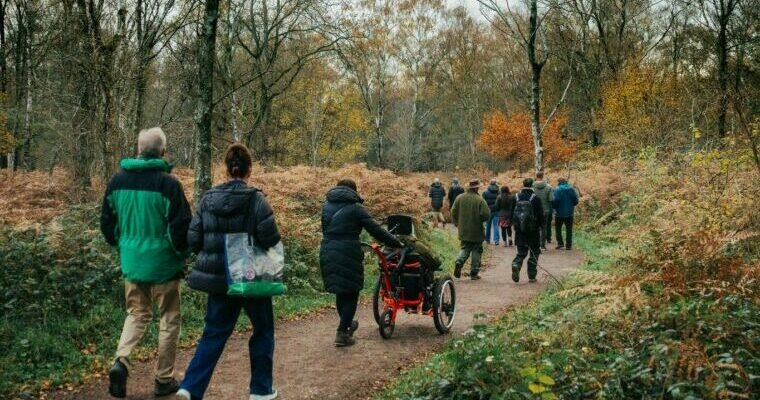 A group of walkers and a person in a wheelchair walk and wheel along an accessible path.