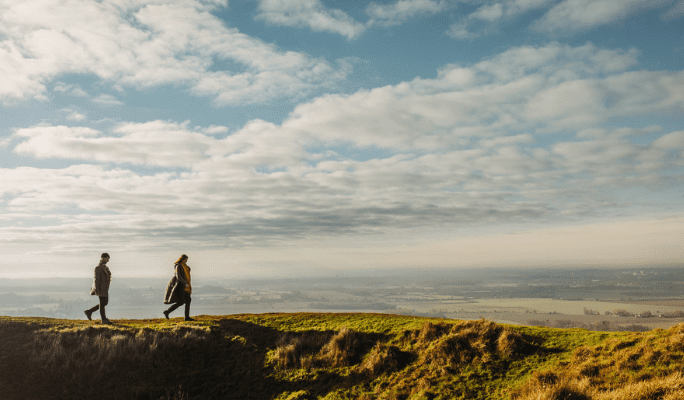 Two people walking along a hilltop in the Wye Downs.